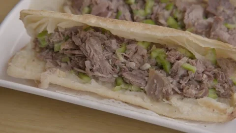 Chopped Meat and Vegetable Flatbread Sandwich Served on Plate in Beijing Street Stock Footage 345789860