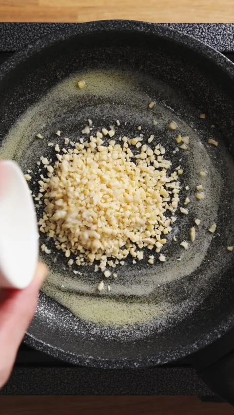 Chopped nuts pour onto melted butter in hot frying pan. Stock Footage 341615683