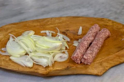 Chopped onion and two raw Kebapche. Stock Photos