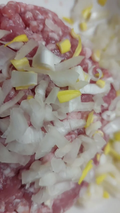 Chopped onions falling on raw minced meat in a bowl Stock Footage 334679879