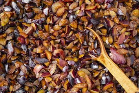 Chopped raw plums boiling for jam cooking process, with a wooden spoon Stock Photos