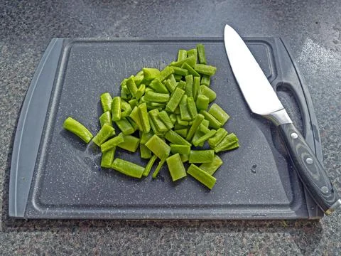 Chopped runner beans with a chefs knife on a chopping board Stock Photos