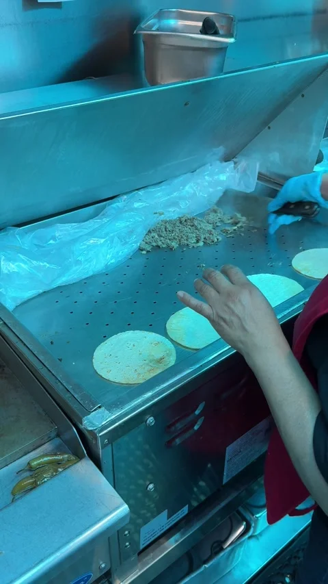 Chopped taco meat and soft tortillas cook side-by-side on a flat grill while Stock Footage 313357901
