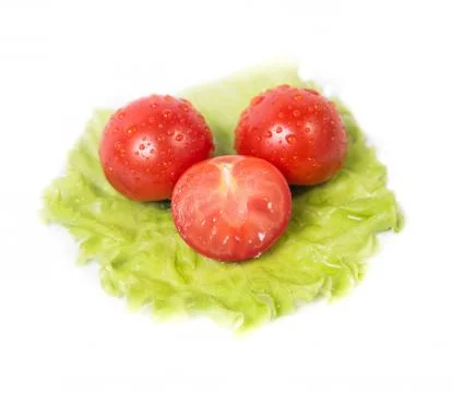 Chopped tomatoes lying on a sheet of green salad Stock Photos