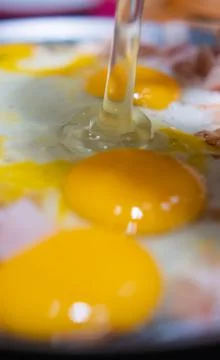 Chopped turkey ham and three egg yolks on a round griddle Stock Photos