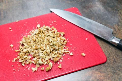 Chopped walnut on red plastic cutting board. Big sharp  chief's knife. View fro 写真素材