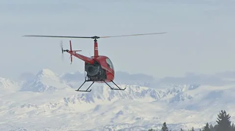 Chopper Hovering Backwards by Snowy Mountains Stock Footage 10841611
