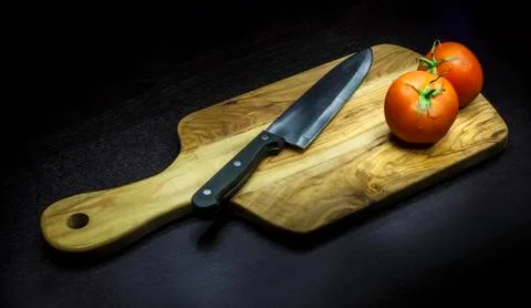 Chopping board with two tomatoes Stock Photos