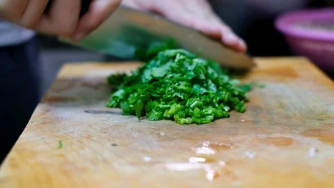 Chopping cilantro on cutting board preparing ingredient for cook Stock Footage 100730167