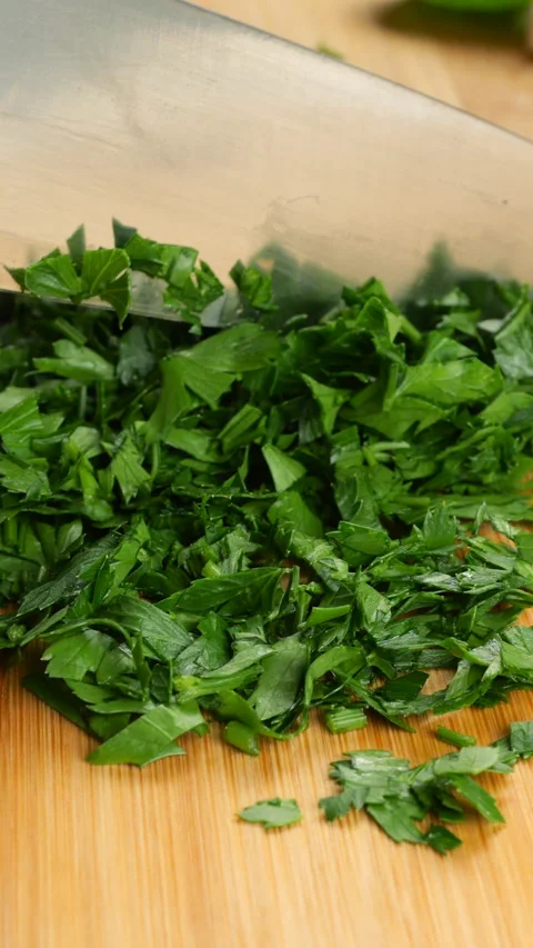 Chopping fresh green parsley with a sharp knife on a bamboo cutting board. Stock Footage 342280485