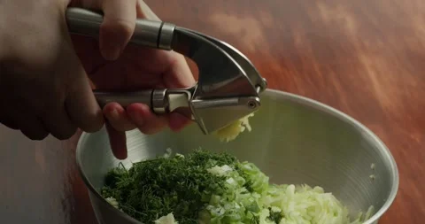 Chopping garlic into a container with dill and green onions. Close-up of a cooks Stock Footage 317550700