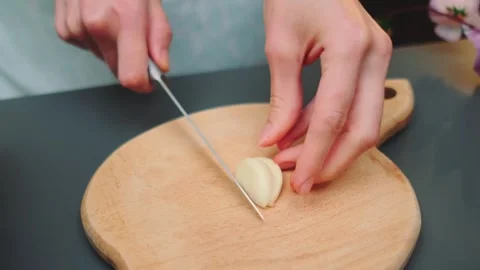 Chopping garlic with a sharp knife on a cutting board Stock Footage 249418566