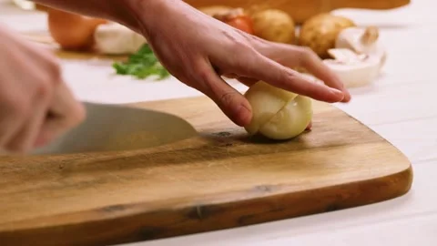 Chopping the onion on the cutting board at the kitchen table Video stock 148200109