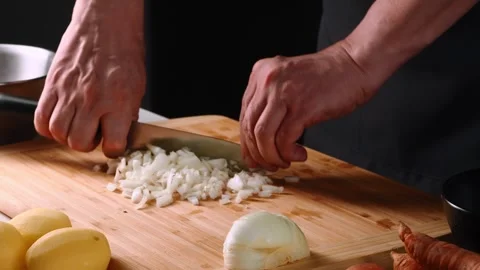 Chopping onions and preparing vegetables on a wooden cutting board in a cozy 動画素材 316631386