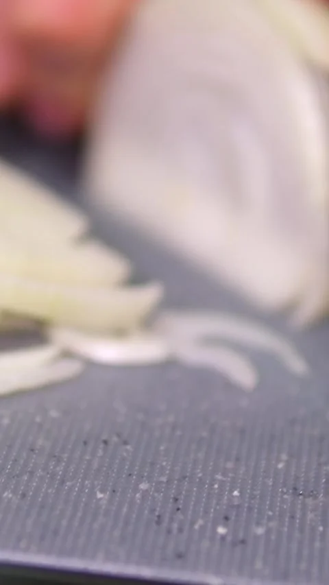 Chopping raw onion with a kitchen knife on a wooden cutting board. Macro shot Stock Footage 302075851
