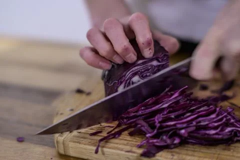 Chopping red cabbage with a kitchen knife on a wooden cutting board Foto stock