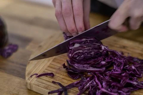Chopping red cabbage with a kitchen knife on a wooden cutting board Stock Photos