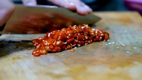 Chopping  red chili pepper on cuting board in kitchen to prepare food Stock Footage 100726166