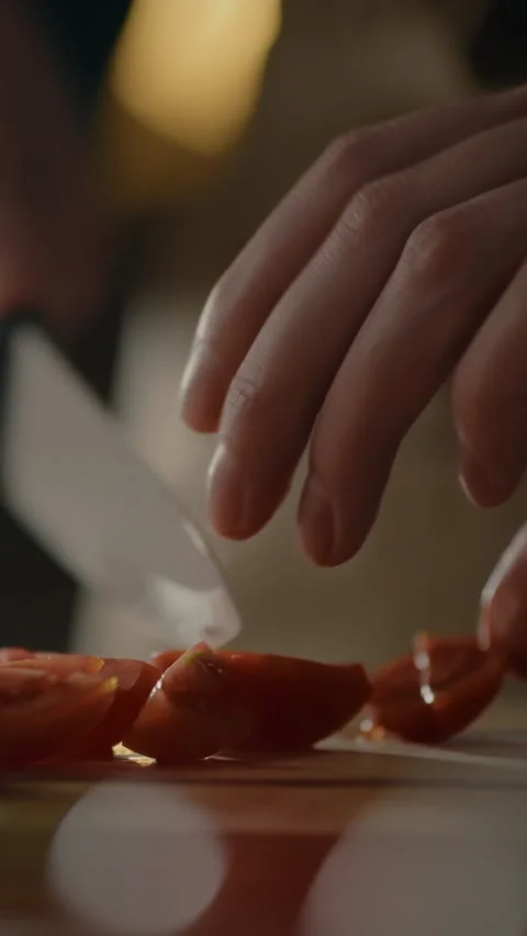Chopping ripe tomatoes with careful hands in a cozy kitchen setting Stock Footage 331537545