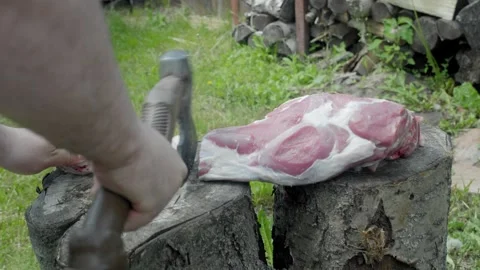 Chopping selected meat from leg bone with axe on tree stumps Stock Footage 248595539