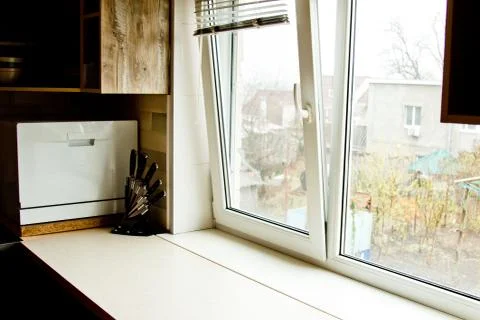 A chopping table with a set of knives in the kitchen against the background o Stock Photos