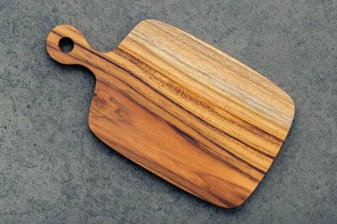 Chopping teak wood cutting board on dark stone background. Stock Photos