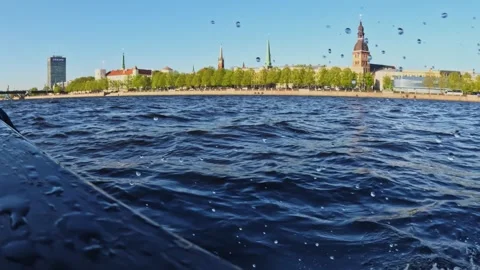 Choppy dark-blue waves hit the boat’s edge while distant spires rise above a Stock Footage 325267812