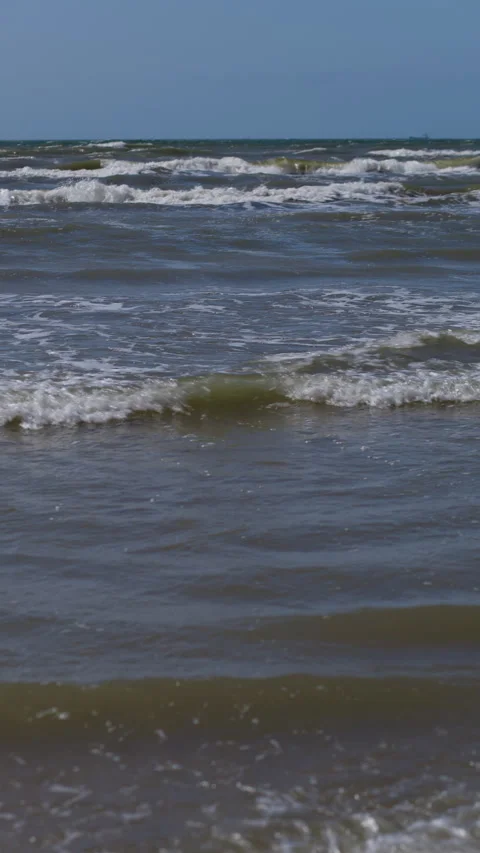 Choppy ocean waves breaking under blue sky with distant ships on horizon Stock Footage 346558961