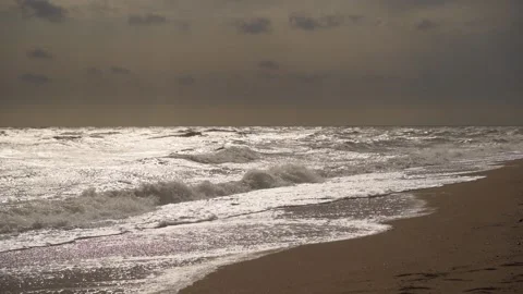 Choppy ocean waves crash onto sandy beach under stormy sky. Rough sea footage Stock Footage 261825112