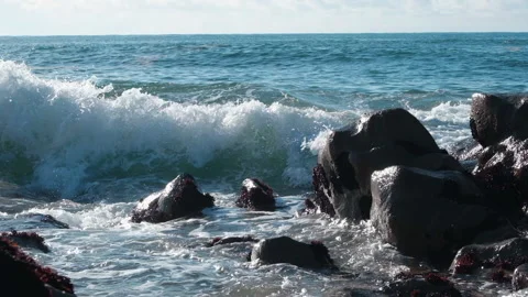 Choppy ocean waves in slow motion, splashing against rocks on the beach shore. Stock Footage 146055004