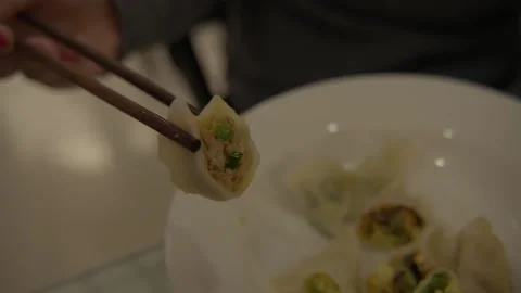 Chopsticks Holding Half Dumpling Over Plate in Beijing Indoor Street Food Stock Footage 345892343