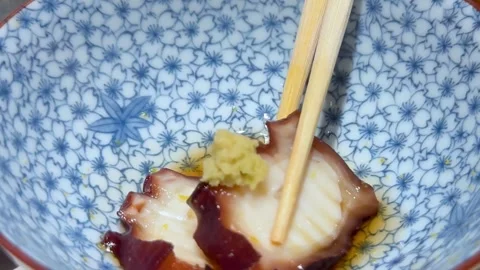 Chopsticks Lifting Octopus from Patterned Bowl Stock Footage 308501372