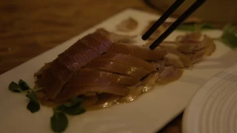 Chopsticks Lifting Sliced Roasted Meat from Platter in Beijing Restaurant Stock Footage 345762963