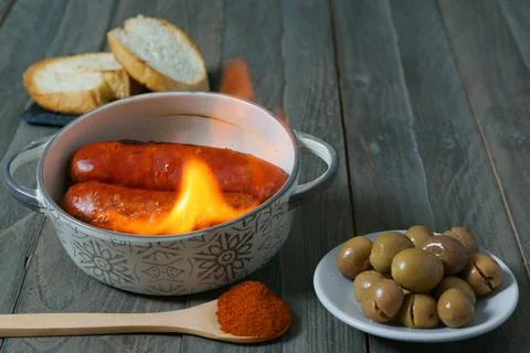 Chorizo grilled chorizo al infierno in a clay pot with bread olives and paprika Stock Photos