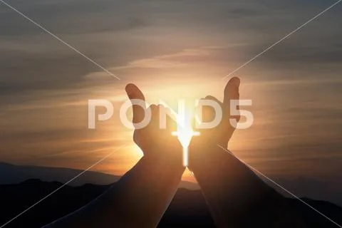 Christian man with open hands, sunshine in the shape of a crucifix and dramat Stock Photos