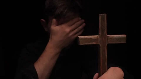 Christian man praying and covering face with hand holding wooden cross Stock Footage 316480853