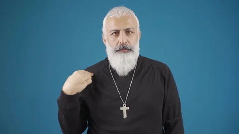 Christian old man looking at camera making the sign of the cross. Stock Footage 228844349