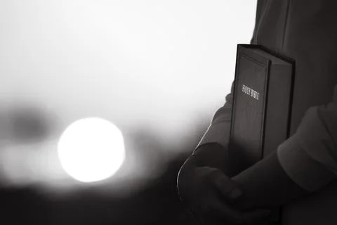 Christian praying while hugging the sunset scenery and the holy bible Stockfoto's