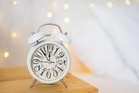 Christmas alarm clock on white table with boken lights. Stock Photos