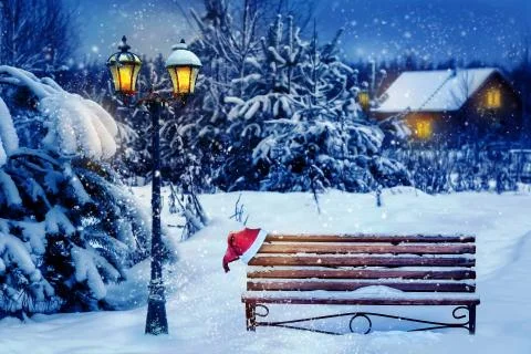 Christmas art card. Santa hat on a bench in the snow against the background o Stock Photos