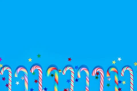 Christmas background with different candy cane and star confetti on blue. Stock Photos