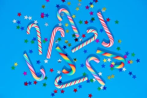 Christmas background with different candy cane and star confetti on blue. Stock Photos