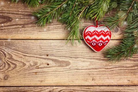 Christmas background with pine branches and knitted heart on old wooden board Stock Photos