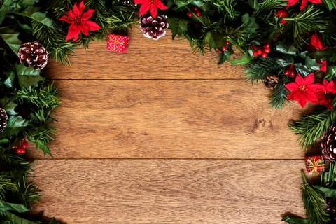 Christmas background with pine branches, red flowers, and cones on wooden boa Stock Photos