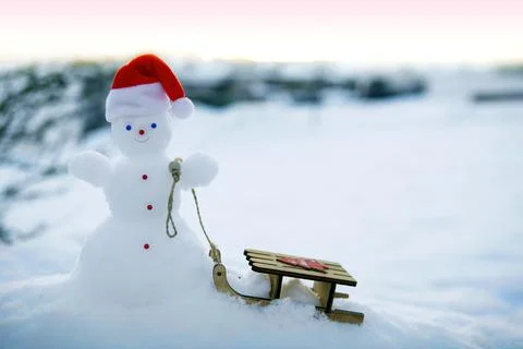 Christmas background with snowman and wood sled stand in white snow. Stock Photos