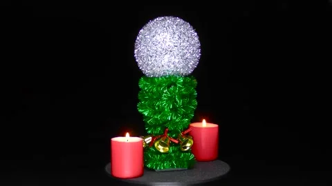 A Christmas ball rotates between two red burning candles Stock Footage 201929780