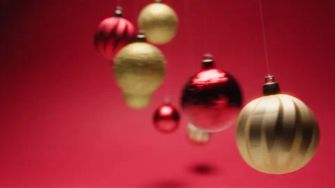 Christmas Balls Swing Like Mesmerizing Hypnotic Pendulums on a Red Background Stock Footage 322975695
