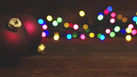 Christmas baubles on rustic table against colourful lights. Stock Footage 285949846