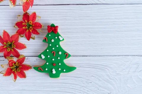 Christmas biscuits in the shape of a tree with red flowers decoration on a .. Stock Photos
