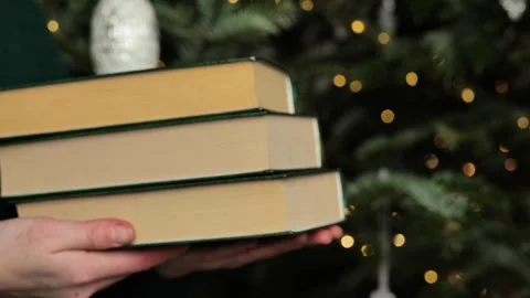 Christmas book .stack of books in a womans hands on Christmas tree background Stock Footage 288120925